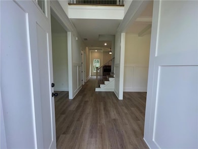 Corridor with wood finished floors, stairs, a decorative wall, and wainscoting