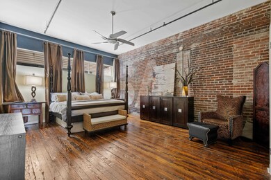 Bedroom with ceiling fan, dark wood-type flooring,