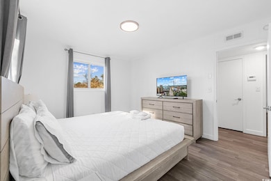 Bedroom with dark wood-type flooring and baseboards