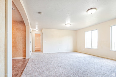 Spare room with arched walkways, light carpet, and a textured ceiling