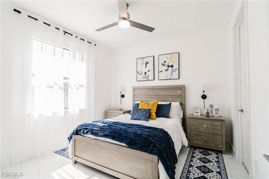 Bedroom featuring a ceiling fan and marble look tile flooring