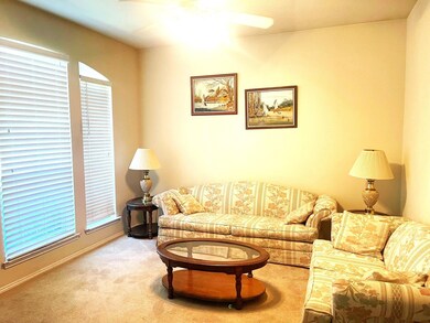 Carpeted living room featuring ceiling fan