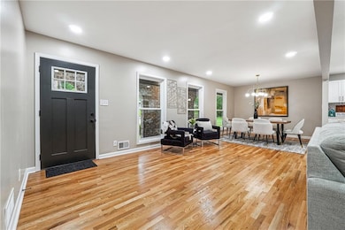 Living area featuring light wood-style floors, baseboards, recessed lighting, and a chandelier
