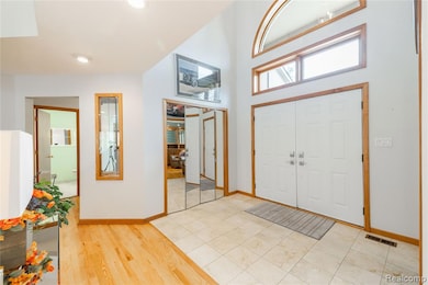 Foyer featuring light wood finished floors, a high ceiling, and recessed lighting