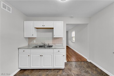 Kitchen featuring white cabinetry, light countertops, backsplash, and stone finish flooring