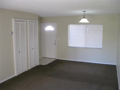 LIVING ROOM SHOWING CLOSETS ON LEFT (WASHER/DRYER HOOK-UPS AND A/C), DINING AREA AND ENTRY.