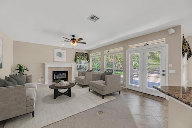 Living room with a tiled fireplace, ceiling fan, 