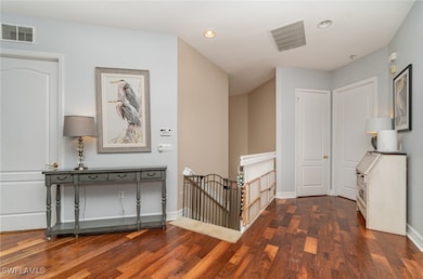 Hallway with an upstairs landing, recessed lighting, and dark wood-style floors