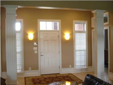 foyer is bright with natural lighting, tile floors, white colums and wall scons. To your right of the foyer is the library with built ins and a very spacious office. To the left is the formal dining room.