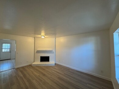 Unfurnished living room with vinyl plank flooring and a brick fireplace