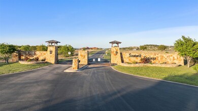 View of asphalt road featuring a gate and a gated