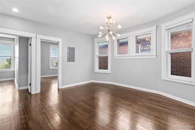 Spare room with a chandelier, dark wood finished floors, and electric panel