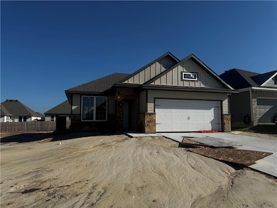 View of front of home with board and batten siding, driveway, stone siding, and a shingled roof