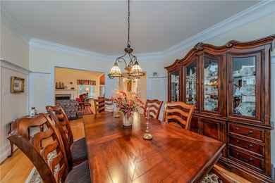 Dining room with crown molding, light wood floors, a chandelier and crown molding