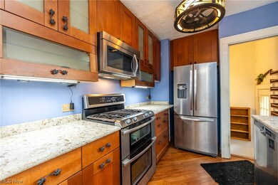 Kitchen with light wood flooring, appliances with stainless steel finishes, and light stone look countertops.