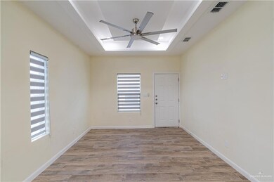 Spare room featuring wood finished floors, a raised ceiling, and ceiling fan