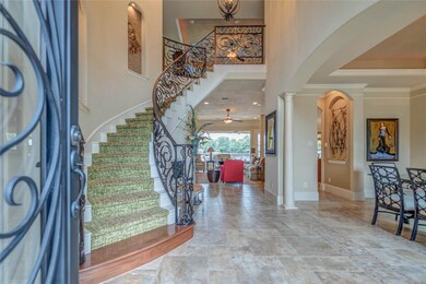 Luxurious entryway with winding staircase, and a view straight through to the water.