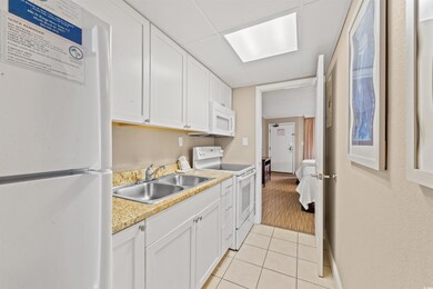 Kitchen featuring light tile patterned flooring, white appliances, sink, and white cabinetry