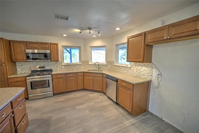 Kitchen featuring brown cabinets, appliances with stainless steel finishes, backsplash, and recessed lighting