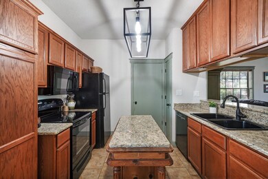Kitchen with sink, black appliances, light tile fl
