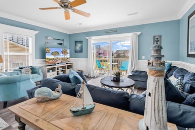 Living area with wood finished floors, crown molding, a ceiling fan, and wainscoting