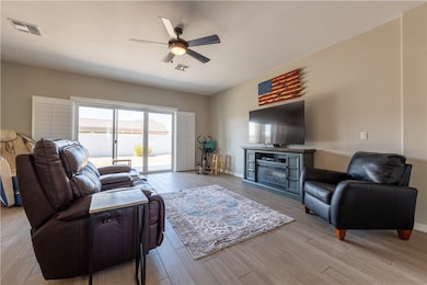 Living room featuring a ceiling fan, light wood-ty