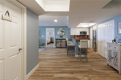 Kitchen with appliances with stainless steel finishes, a breakfast bar area, light wood-style floors, crown molding, and recessed lighting
