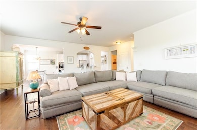 Living area with ceiling fan, arched walkways, dark wood-style flooring, a fireplace, and ornamental molding