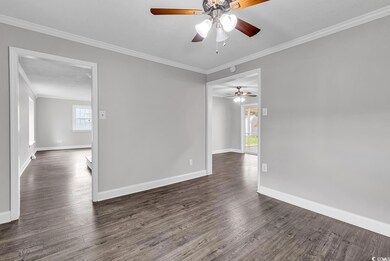 Spare room with crown molding, a ceiling fan, and dark wood-style floors