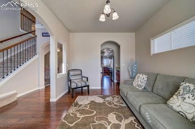 Living area with arched walkways, stairs, a wealth of natural light, and wood finished floors