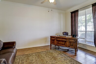 Handsome Study with French doors, wood flooring, crown molding, and ceiling fan.