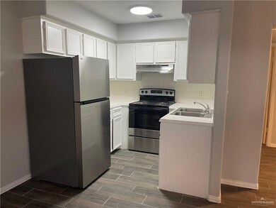 Kitchen with sink, decorative backsplash, white cabinets, and appliances with stainless steel finishes