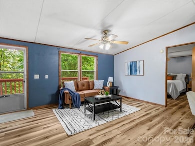 Open living and bedroom area with hardwood flooring, ceiling fan, and French doors to deck. - 2271 Gouges Creek Rd, Spruce Pine, NC 28777