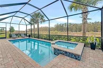 View of swimming pool featuring glass enclosure, a sunroom, a pool with connected hot tub, and a patio area
