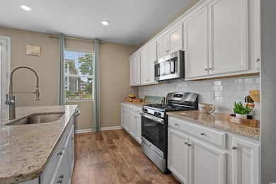Kitchen with appliances with stainless steel finishes, dark wood finished floors, tasteful backsplash, white cabinets, and recessed lighting