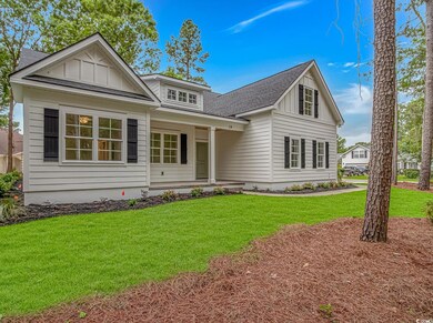 View of front of house with board and batten siding, a front lawn, covered porch, and roof with shingles