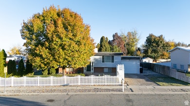 View of front of home with concrete driveway, a fenced front yard, and a garage