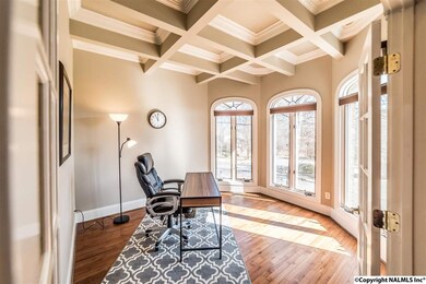 Light pours into the home office, featuring french doors, coffered ceilings, and built-in shelving