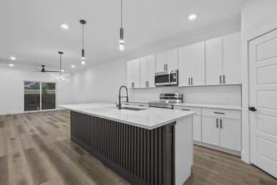 Kitchen featuring a center island with sink, appli