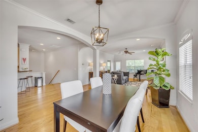 Dining space featuring arched walkways, light woo