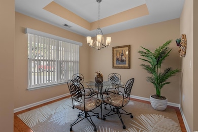 Dining room featuring a raised ceiling, a chandelier, and wood finished floors