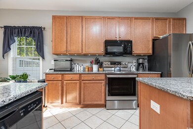 Kitchen with black appliances, light stone countertops, and light tile patterned floors