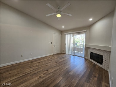 Unfurnished living room featuring vaulted ceiling, dark wood-type flooring, a tile fireplace, recessed lighting, and ceiling fan