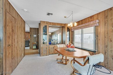 Carpeted dining area with wood walls, visible vent