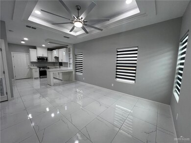 Kitchen with a raised ceiling, a ceiling fan, white cabinetry, light countertops, and open floor plan