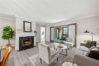 Living area featuring a tile fireplace, wood finished floors, crown molding, baseboards, and a textured ceiling