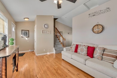 Living room featuring light wood-style floors, stairs, vaulted ceiling, and a ceiling fan