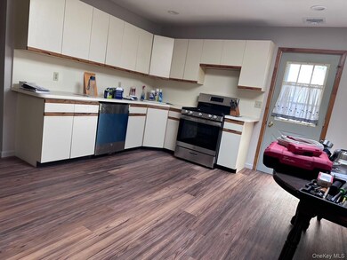 Kitchen with white cabinets, stainless steel range oven, light countertops, dark wood-type flooring, and dishwashing machine