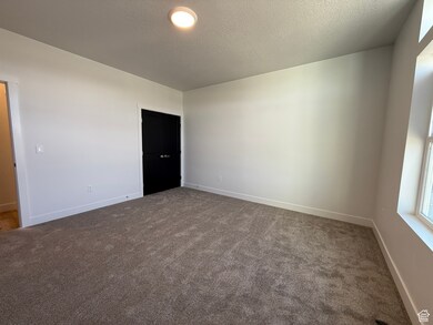 Unfurnished room featuring a textured ceiling and dark colored carpet