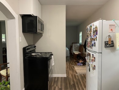 Kitchen featuring freestanding refrigerator, black / electric stove, stainless steel microwave, dark wood finished floors, and white cabinets